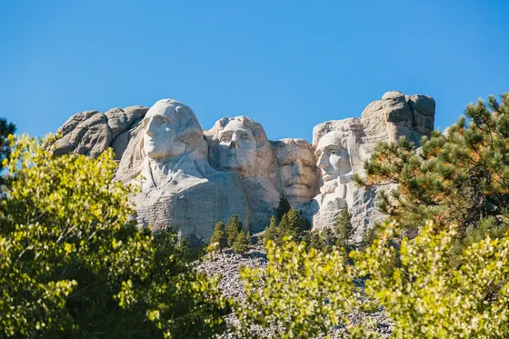 Mount Rushmore rising above green pine trees