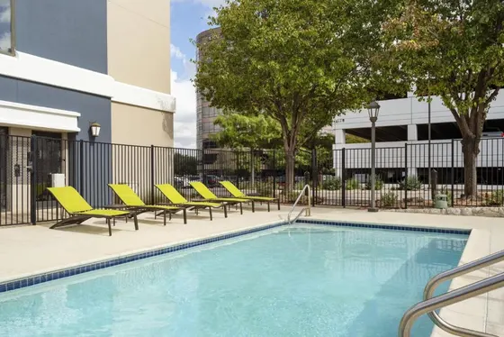 Pool with lime-green lounge chairs behind a black fence