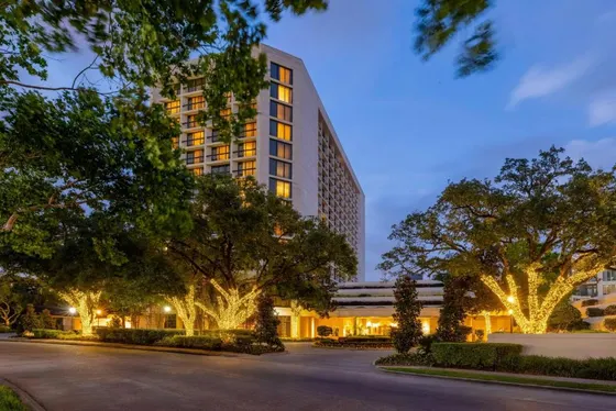 Multi-story hotel at dusk with trees wrapped in white lights