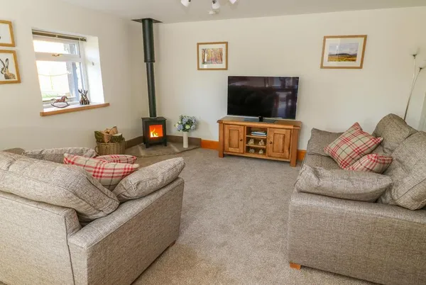 Stable View Cottage lounge with wood-burning stove and armchairs