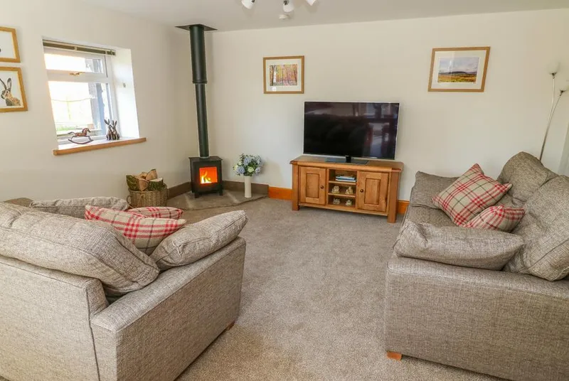 Stable View Cottage lounge with wood-burning stove and armchairs