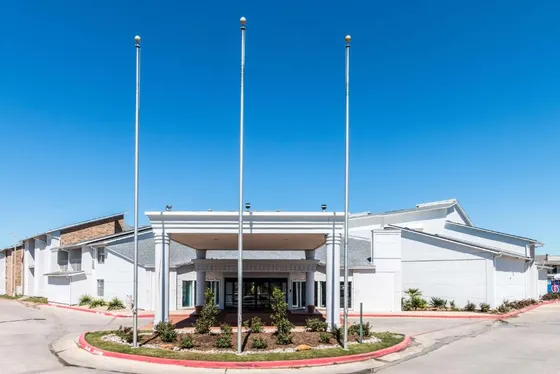 White porte-cochere with flagpoles and a Motel 6 sign behind
