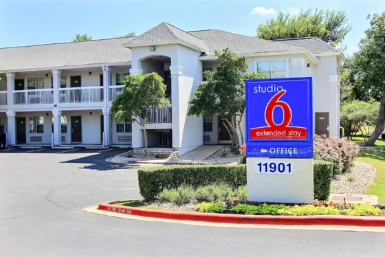 Blue Studio 6 sign in front of a beige two-story motel