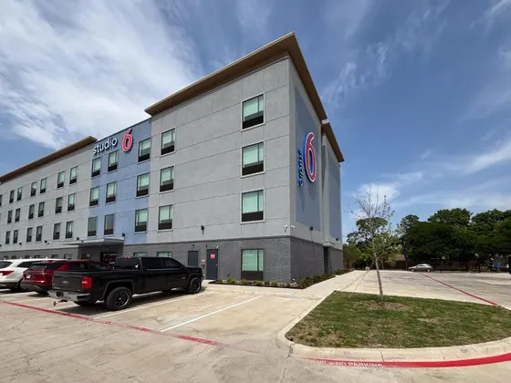 Gray hotel with a Studio 6 sign and parked cars
