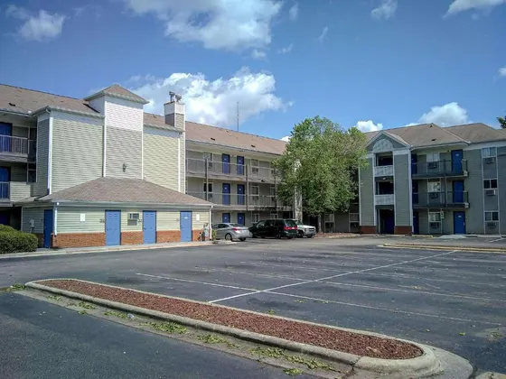 Three-story motel buildings with outdoor walkways around a parking lot