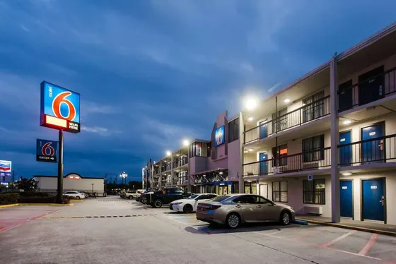 Two-story motel with blue doors and an illuminated sign at twilight
