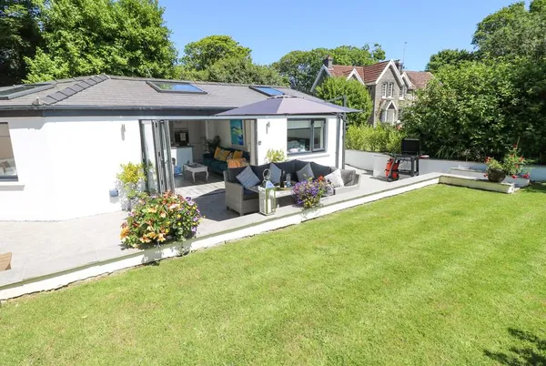 Summerhouse bungalow with bifold doors open to green lawn and mature trees