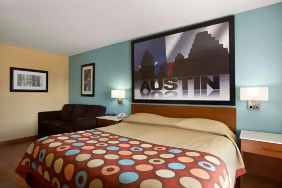 Room with a polka-dot bedspread and an Austin skyline mural