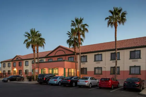 Building with cars parked in a parking lot with palm trees