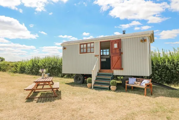 Sweet Caroline Shepherd's Hut cream wagon hut beside picnic bench
