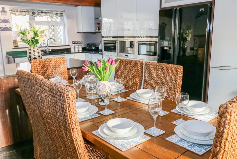 Swn y mor dining table styled with wine glasses, flowers and wicker chairs