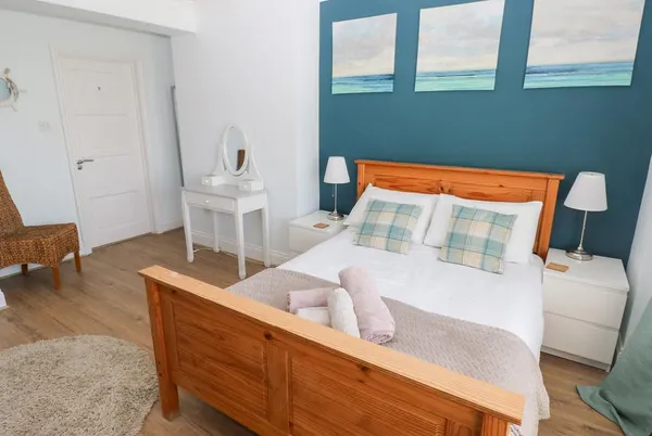 Swn y mor king bedroom with teal feature wall and sea triptych artwork