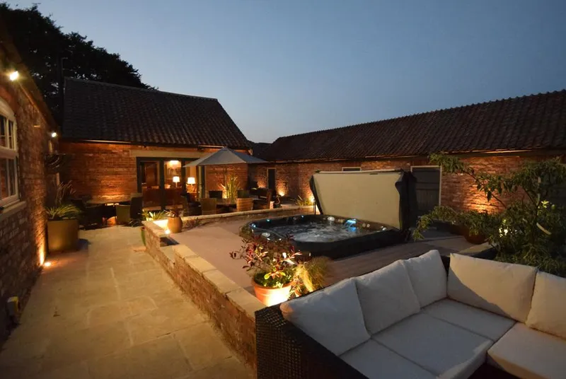 Sykes Lodge hot tub in courtyard at dusk with uplighting