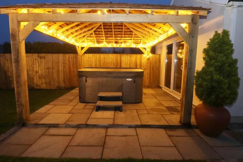 The Elms evening hot tub beneath a lit timber pergola