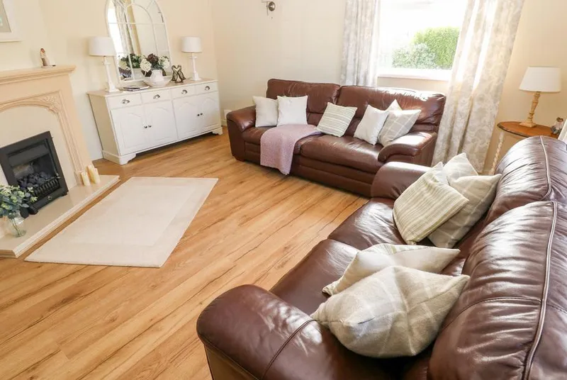 The Elms sitting room with leather sofas and neutral styling