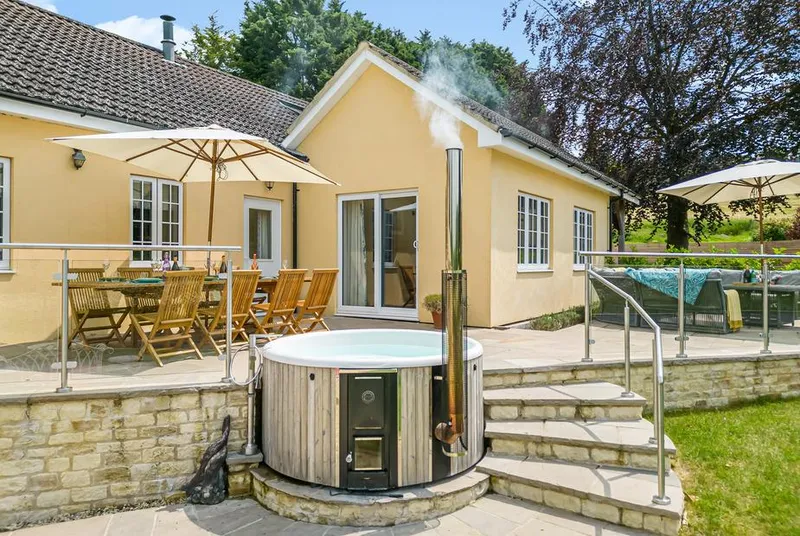 The Anchorage wood-fired hot tub with steam rising on stone patio