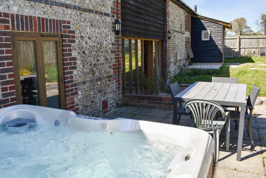 The Barn bubbling hot tub with flint barn wall behind