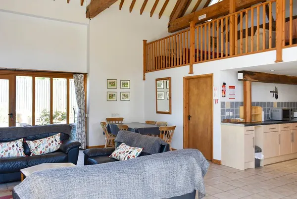 The Barn open-plan living area with vaulted beamed ceiling and mezzanine