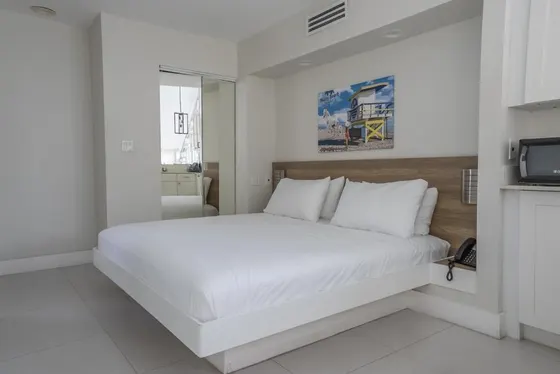 White bedroom with a large bed and a television