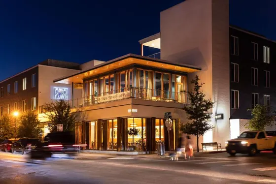 Lit glass corner building at night with a Sip Splash Stay banner