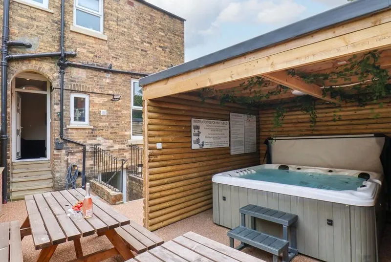 The Corner House hot tub in covered gazebo with courtyard and picnic bench