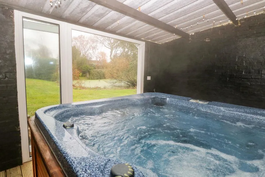 The Duck House indoor hot tub bubbling with garden view through glass doors