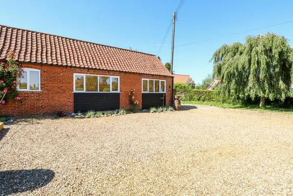 The Duck House brick barn conversion with weeping willow and blue sky