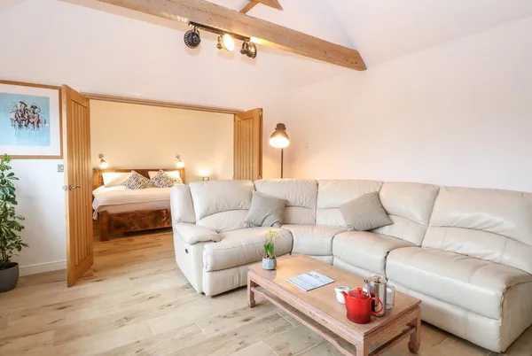 The Duck House living room with leather sofa and bedroom through oak doors
