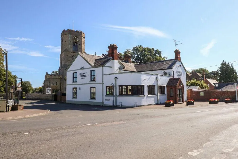 The Five Bells Inn converted pub exterior with church tower behind