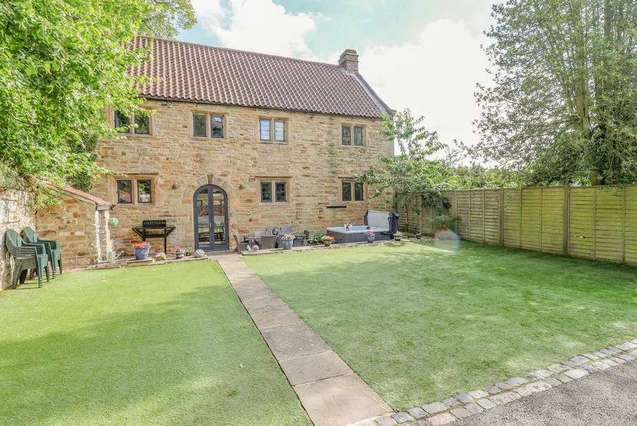 The Gatehouse stone courtyard exterior with lawn and hot tub
