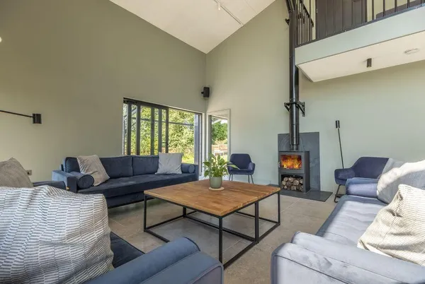 The Grain Store double-height living room with lit wood burner and mezzanine