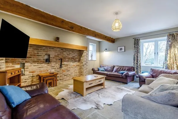 The Hay Barn living room with exposed beam and brick wall