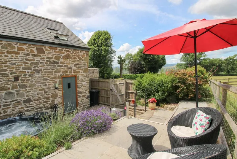 The Hay Loft patio with red umbrella and partial hot tub