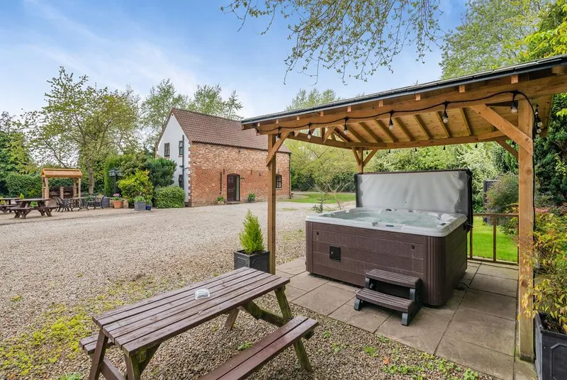 The Hayloft shared hot tub under wooden pergola with festoon lights