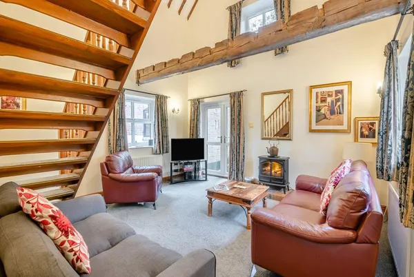 The Hayloft double-height living room with exposed beam and wood burner