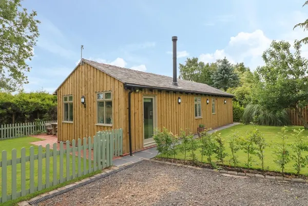The Hen House timber lodge with green picket gate and blue sky