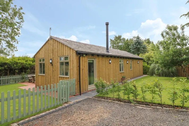 The Hen House timber lodge with green picket gate and blue sky