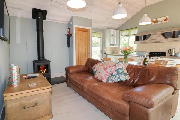 The Hen House open-plan living room with leather sofa and wood burner