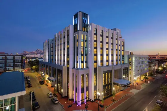 Lit Higgins hotel at dusk with a steel bridge behind it