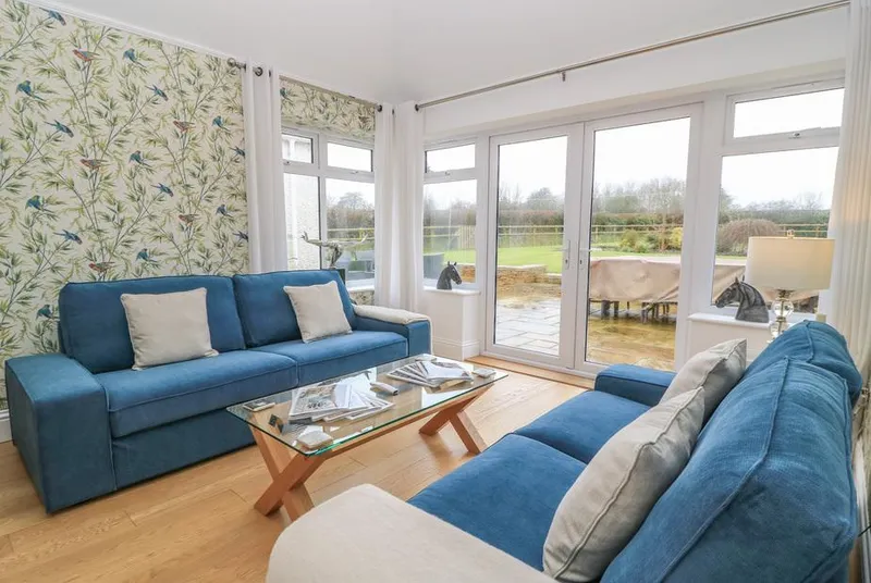 The Little Paddock snug with blue velvet sofas and countryside views through French doors
