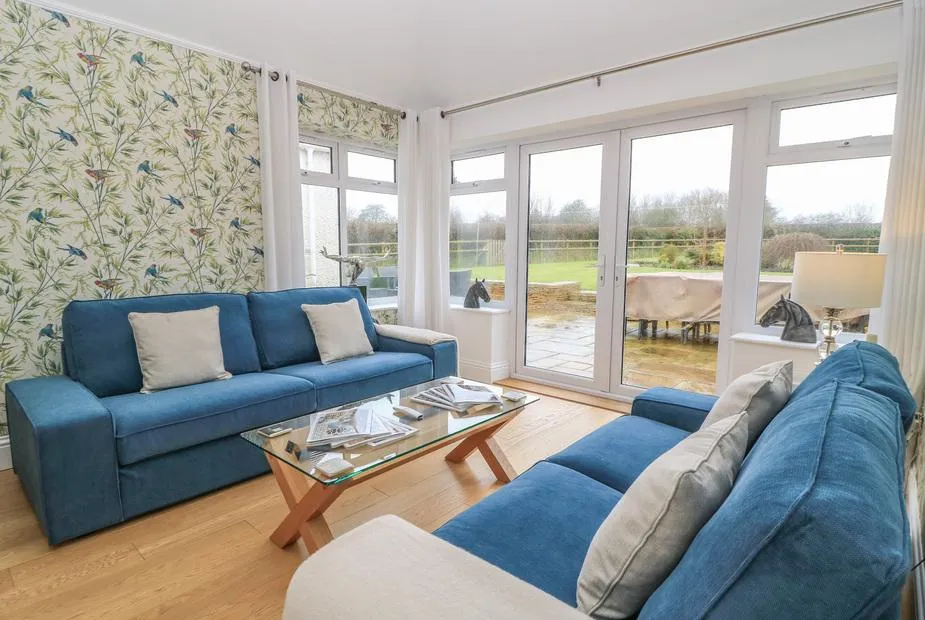 The Little Paddock snug with blue velvet sofas and countryside views through French doors