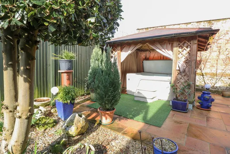 The Lodge hot tub gazebo with curtains in landscaped garden