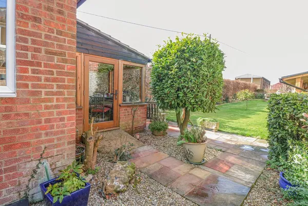 The Lodge garden side with French doors and manicured bay tree