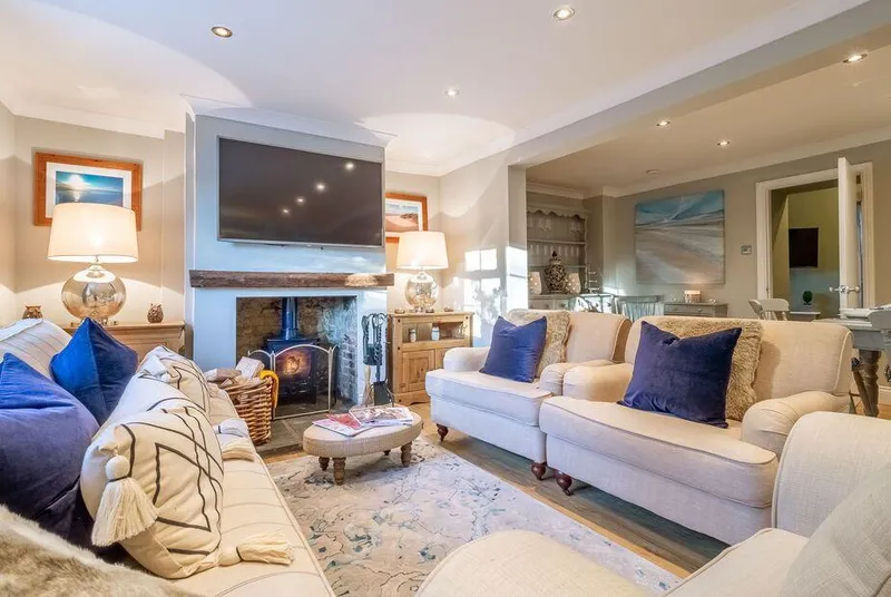 The Malthouse Dersingham living room with lit wood burner and cream sofas