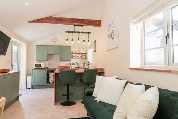 The Nest open-plan living and kitchen with green sofa and sage units