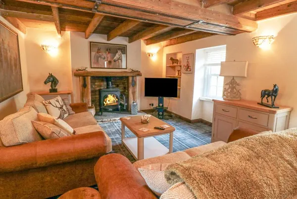 The Nook living room with woodburning stove, exposed beams and leather sofas