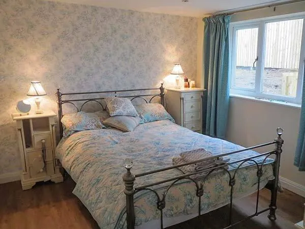 The Old Corn Store romantic bedroom with iron bedframe and blue floral decor