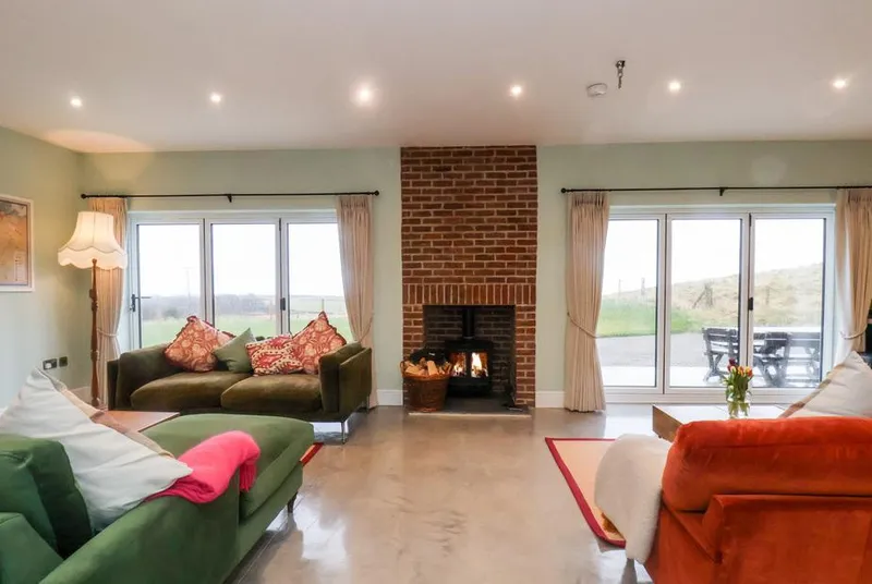 The Old Guard House living room with lit log burner and countryside views through bi-fold doors