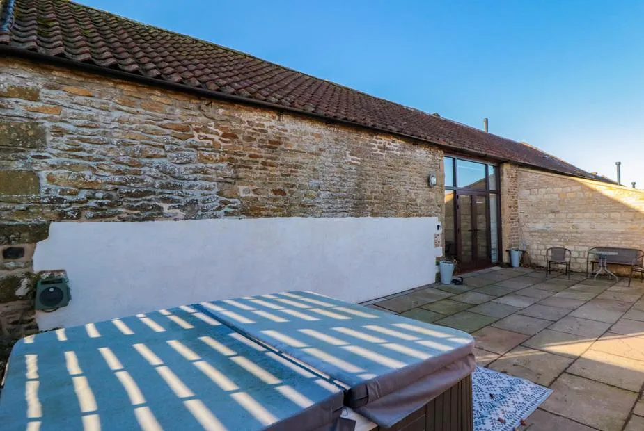 The Old Workshop hot tub in sunny stone courtyard