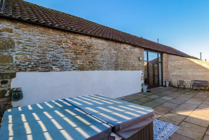 The Old Workshop hot tub in sunny stone courtyard